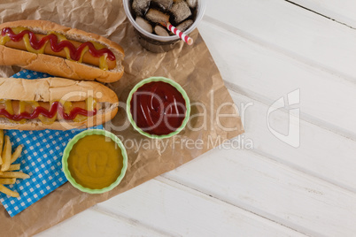 Hot dog, sauces and cold drink on brown paper