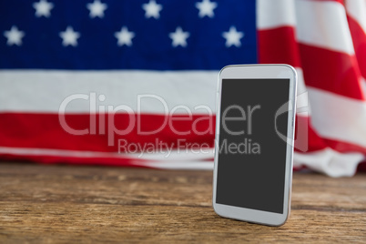 American flag and mobile phone arranged on wooden table