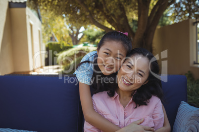 Mother and daughter relaxing on couch outside home