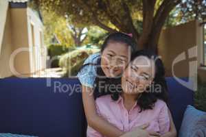 Mother and daughter relaxing on couch outside home