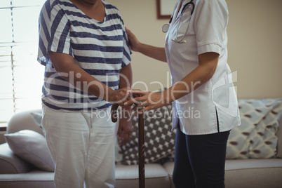 Female doctor helping senior woman to walk with walking stick