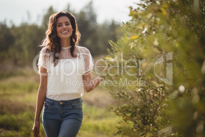 Beautiful young woman standing by trees at olive farm