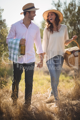 Cheerful young couple carrying picnic basket