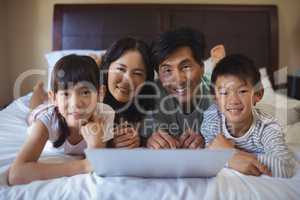 Family using laptop together in bedroom at home