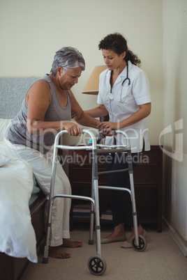 Female doctor helping senior woman to walk with walker