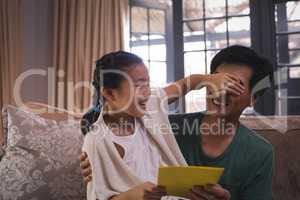 Daughter giving greeting card to father in living room