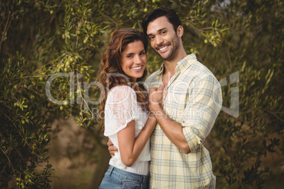 Loving young couple standing by trees at olive farm