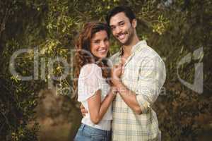 Loving young couple standing by trees at olive farm