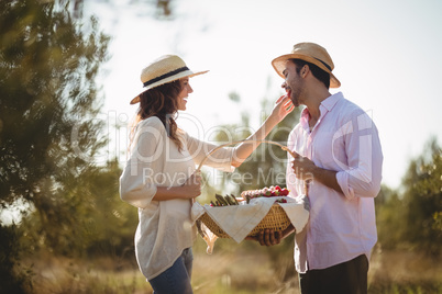 Happy young woman feeding boyfriend at farm