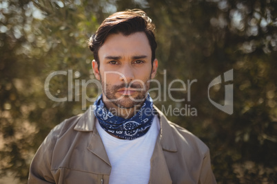 Portrait of young man standing at olive farm on sunny day