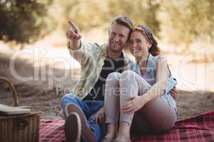 Young man showing something to woman while sitting at olive farm