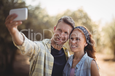 Cheerful young couple taking selfie at olive farm