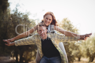 Smiling man piggybacking woman at olive farm