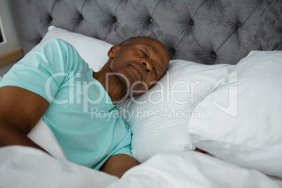 Carefree senior man sleeping on bed