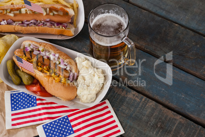 Hot dog and glass of beer with american flag on wooden table