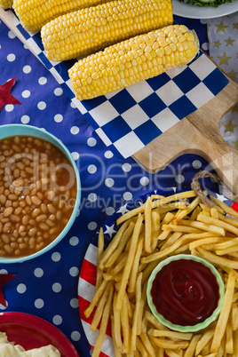 French fries and corn cob on wooden table with 4th july theme