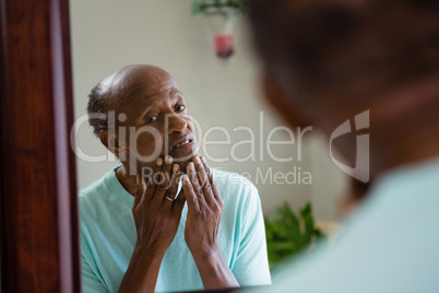 Concerned senior man looking at mirror