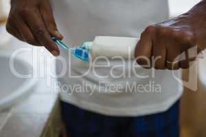 Mid section of man applying toothpaste on brush