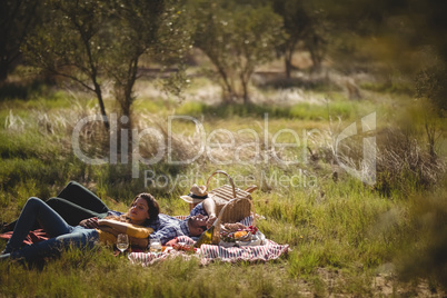 Young couple resting together on picnic blanket at olive farm
