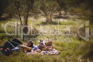 Young couple resting together on picnic blanket at olive farm