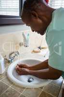 Senior man collecting water from faucet at sink