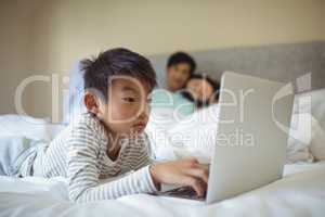 Boy using laptop in bedroom