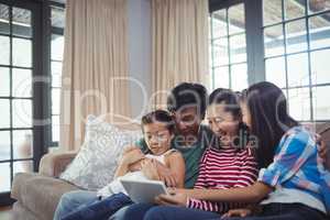 Smiling family using digital tablet together in living room