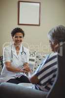 Female doctor comforting senior woman in living room