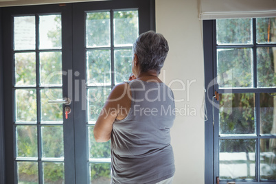 Thoughtful senior woman looking through window in bed room