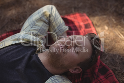 Young man sleeping on mat at farm