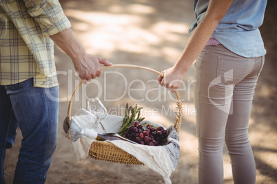 Mid section of couple carrying basket at farm