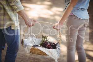 Mid section of couple carrying basket at farm