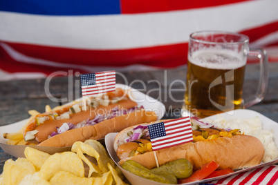 Hot dog and glass of beer with american flag on wooden table