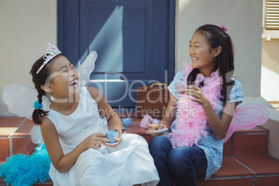 Siblings in fairy costume having a tea party