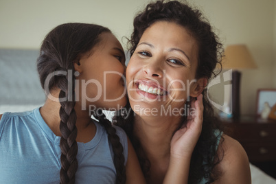 Daughter kissing mother on cheeks in bed room