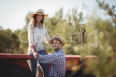 Portrait of happy man holding girlfriend standing on tractor