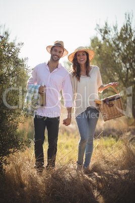 Portrait of happy young couple carrying picnic basket