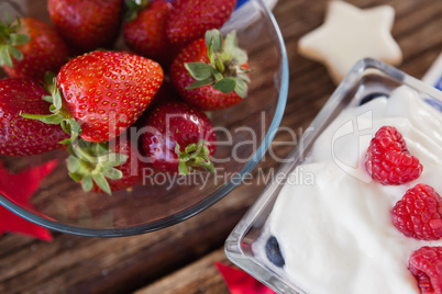 Strawberries in bowl with sweet food on wooden table