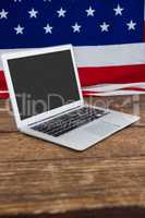 Laptop and American flag on wooden table