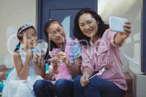 Siblings in fairy costume and mother taking a selfie on mobile phone