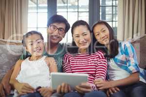 Smiling family using digital tablet together in living room