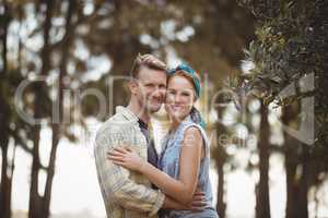 Smiling young couple embracing by olive tree at farm