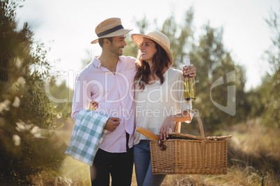 Happy young couple looking at each other while carrying picnic basket