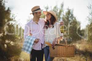 Happy young couple looking at each other while carrying picnic basket