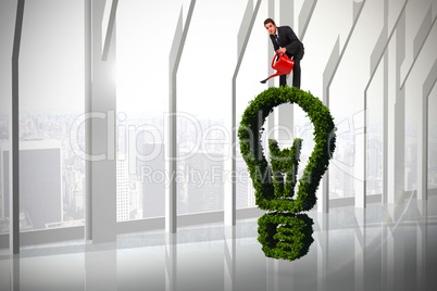 Composite image of businessman watering with red can