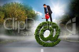 Composite image of businessman holding red watering can