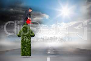 Composite image of mature businessman using watering can