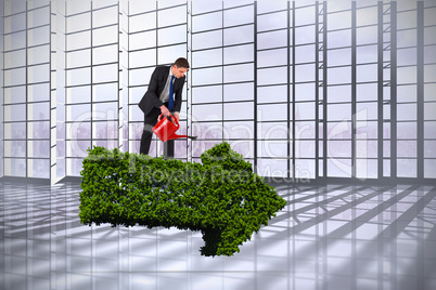 Composite image of businessman holding red watering can