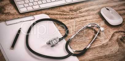 Stethoscope with clipboard by keyboard and mouse on table