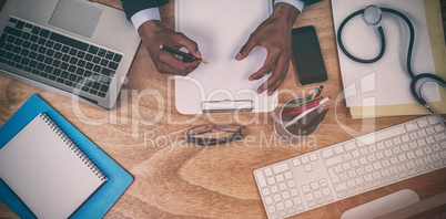 Cropped hands of male doctor writing prescription